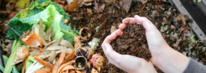 Hände, die Kompost über dem Kompost mit organischen Abfällen halten